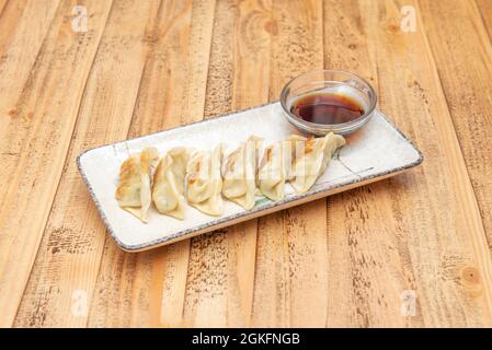 Popular plate of Asian dumplings fried grilled gyozas with soy sauce to dip on a beautiful white plate Stock Photo