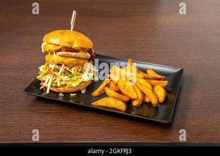 Double burger with lots of melted cheddar cheese, straw potatoes, bacon, lettuce, mayonnaise, mustard and ketchup with a side of deluxe fries Stock Photo