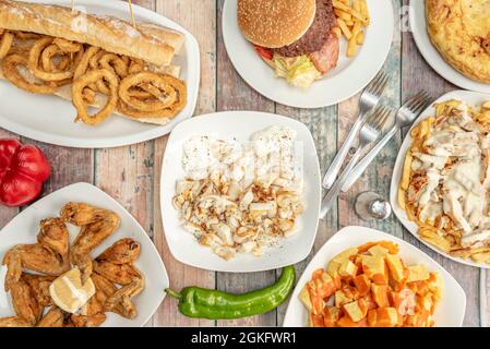 Popular tapas served in a Spanish restaurant. Patatas bravas, lemon chicken wings, squid sandwich, grilled cuttlefish with alioli, potato omelette. Stock Photo