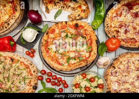 Set of pizzas and Italian dishes. Calzone, arrabiata pizza, carbonara pizza, rucola pizza, cherry tomato branch, burrata, garlic and peppers. Stock Photo