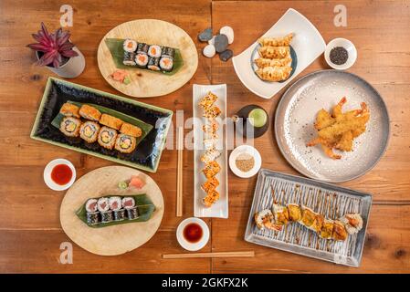 Top view image of Japanese food sticks. Shrimp in tempura, california roll, salmon and red tuna maki, fried gyozas, soy sauce, sesame seeds, dragon ro Stock Photo