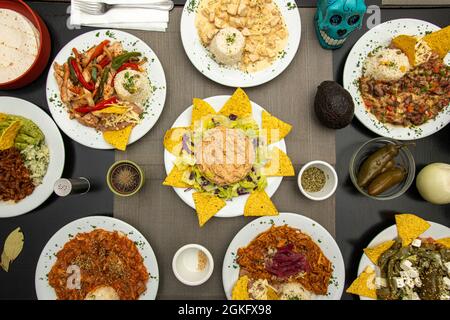 Set of Mexican food dishes with fajitas, peppers, corn chips, chicken tinga stew, pumpkin flower chicken, nopales with cheese, ripe avocado and jalape Stock Photo