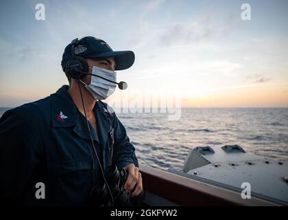 A lookout stands watch on the bridge of the guided missile frigate