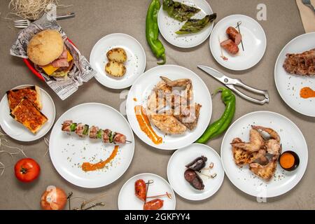 set of dishes made in a restaurant with a charcoal grill. Roasted sausages, chicken and vegetable skewers, charcoal chicken, barbecue wings, roasted p Stock Photo