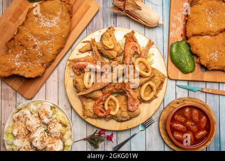 Plates of popular Spanish food in tapas restaurant. Hell chorizos, roasted potatoes, fried fish, full Asturian cachopo. Stock Photo