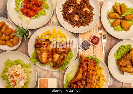 Food plates for tapas restaurant. Roast chicken with french fries, chaufa aroz, tiger mussels, ham croquettes, meatloaf with tomato, Russian salad, ba Stock Photo