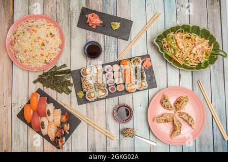 Chinese food and sushi dishes set. Sushi, maki and uramaki assorted. Noodles with prawns, three delights rice, red tuna nigiri, Norwegian salmon, stew Stock Photo