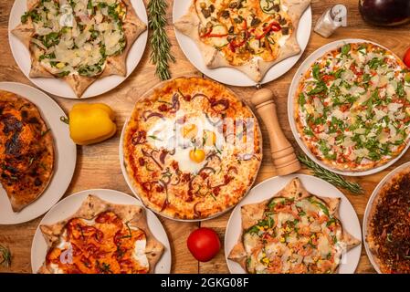 Assorted pizzas seen from the top. With fried eggs, with arugula muhca and flaked parmesan cheese, a calzone, with Norwegian salmon, with nopales and Stock Photo