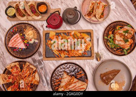 Set of delicious dishes of popular Mexican food, nachos with guacamole, cochinita tacos, full burrito, synchronized quesadillas, tacos al pastor Stock Photo