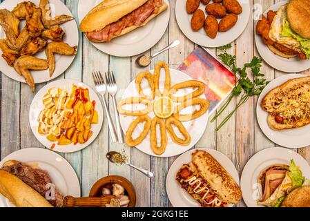set of typical food dishes served in Spanish taverns. Squid a la romana, patatas bravas, fried wings, bacon sandwich, homemade croquettes Stock Photo
