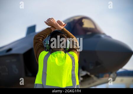 U.S. Air Force Senior Airman Bradley Freerksen, a 356th Aircraft Maintenance Unit crew chief, guides an F-35A Lightning II pilot during a hot pit refueling on Eielson Air Force Base, Alaska, April 13, 2021. As a crew chief, Freerksen is responsible for performing special pre and post-flight aircraft inspections to ensure pilots can safely and effectively complete their mission. Stock Photo