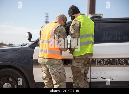 U.S. Army Staff Sgt. Joshua Waldron, left, and Cpl. Elijah Miles, right, cavalry scouts assigned to 3rd Squadron, 61st Cavalry Regiment, screen a Pueblo police officer prior to receiving a vaccination at the Pueblo Community Vaccination Center at the Colorado State Fairgrounds in Pueblo, Colorado, April 14, 2021. The Soldiers deployed from Fort Carson, Colorado to administer vaccinations to members of the Pueblo community. U.S. Northern Command, through U.S. Army North, remains committed to providing continued, flexible Department of Defense support to the Federal Emergency Management Agency a Stock Photo