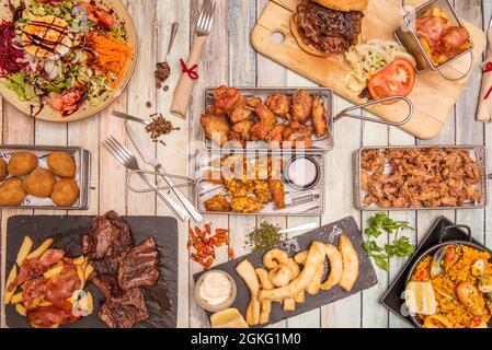 Various dishes of popular Spanish food. Entrecote, goat salad, croquettes, wings, squid, lace, paella, tapas, squid squid Stock Photo