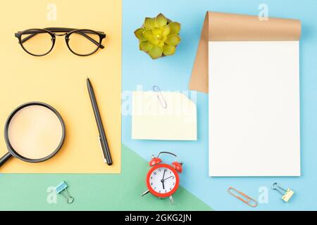 White notepad glasses pencil on blue background Stock Photo