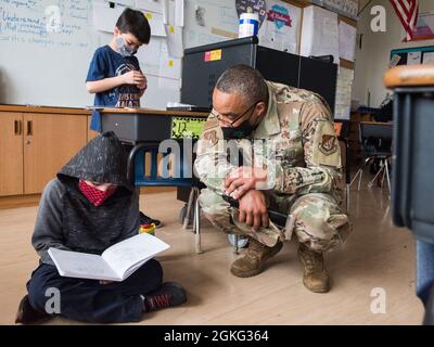 U.S. Air Force Chief Master Sgt. Plez Glenn, the 35th Fighter Wing Maintenance Group superintendent, helps a student from the Sollars Elementary School, review notes taken in class during a Wild Weasel Walk-Through at Misawa Air Base, Japan, April 13, 2021. On average, military children change schools up to nine times between the start of kindergarten and high school graduation. Stock Photo