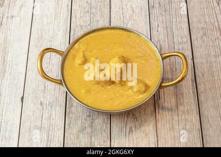 Bowl with mild chicken korma yellow curry with yogurt sauce and coconut milk on white table Stock Photo