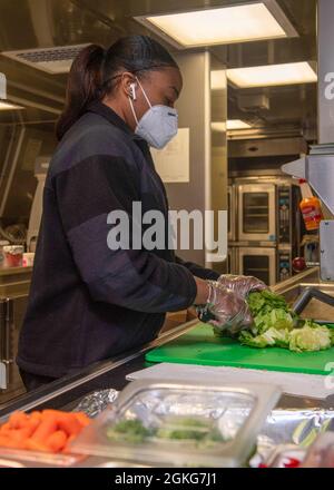 PACIFIC OCEAN (April 14, 2021) Culinary Specialist 1st Class Leshannen Strickland from Jackson, Ga., chops lettuce aboard Independence-variant littoral combat ship USS Charleston (LCS 18), April 14. Charleston is currently operating in U.S. 3rd Fleet. Stock Photo