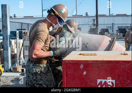 210415-N-TP832-1040 PORT HUENEME, Calif. (April 15, 2021) Builder Constructionman Ian Hasselbalch and Builder Constructionman Darren Toman, assigned to U.S. Naval Mobile Construction Battalion (NMCB) 3, pour cement into a concrete mixer to place a slab as part of a Seabee Technical Training Module on board Naval Base Ventura County, Port Hueneme. Seabees are the expeditionary engineering and construction experts of the naval service. They provide task-tailored, adaptable and combat-ready engineering and construction forces that deploy to support Navy objectives globally. Stock Photo