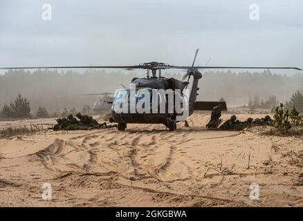 Canadian Land forces soldiers of the Royal Canadian Dragoons, 2nd Canadian Mechanized Brigade Group, dismounts a U.S. Army Blackhawk in the early morning hours of Apr. 16. The unit was on a joint exercise with 3rd Battalion, 1st Combat Aviation Brigade, 1st Infantry Division, to clear the area of enemy in the mountainous wooded border region near Lielvarde, Latvia. Stock Photo