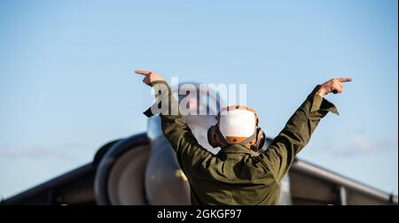 Marine Pfc. Byrd, a plane captain from Marine Attack Squadron 223, Cherry Point, North Carolina, gives hand signals to an AV-8B Harrier pilot at Gowen Field, Boise, Idaho, April 16, 2021. The commands help test various systems on the aircraft before it flies. Stock Photo