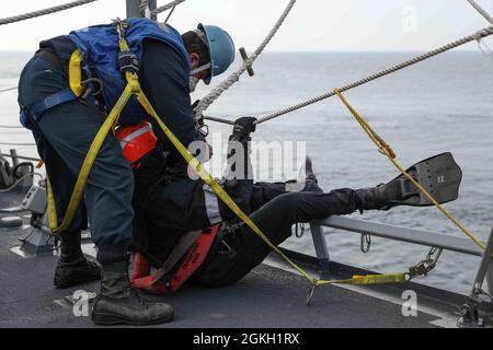 ENGLISH CHANNEL (April 20, 2021) Boatswain’s Mate Seaman Rodrigo Solis, left, prepares Seaman Douglas Malin to be lowered into the water for search and rescue during a man overboard drill aboard the Arleigh Burke-class guided-missile destroyer USS Ross (DDG 71) during Flag Officer Sea Training (FOST), April 20, 2021. FOST is a three-week exercise led by the Royal Navy that tests the ship’s warfighting ability. Ross, forward-deployed to Rota, Spain, is on patrol in the U.S. Sixth Fleet area of operations in support of regional allies and partners and U.S. national security interests in Europe a Stock Photo