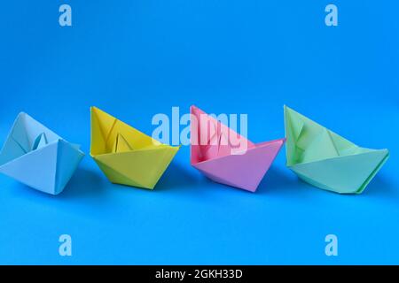 Colored paper boats on blue background Stock Photo