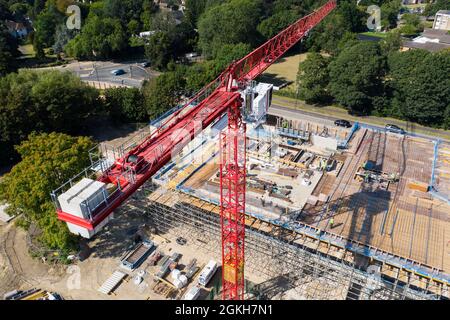 Aerial view of a tall construction crane lifting building materials onto the roof of a new build warehouse Stock Photo
