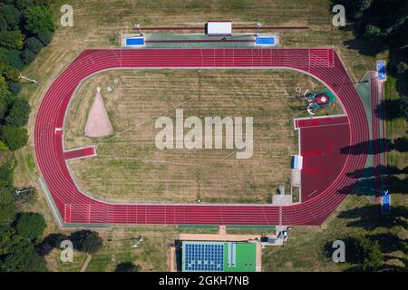 An aerial view of an outdoor athletics stadium with red, oval running track and facilities for sport Stock Photo