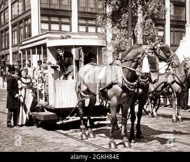 1950s HORSE DRAWN TROLLEY TURN OF CENTURY STREET CAR ON BRICK STREET WITH PASSENGERS WEARING 1890s ERA COSTUMES GETTING ON BOARD - c824 HAR001 HARS ROMANCE COMMUNITY STONE URBAN GETTING OLD TIME CONDUCTOR NOSTALGIA OLD FASHION 1 JUVENILE BLOCK HORSES TEAMWORK TURN COSTUMES LIFESTYLE ACTOR HISTORY BRICK CELEBRATION FEMALES PASSENGERS COPY SPACE FULL-LENGTH LADIES PERSONS MALES ENTERTAINMENT TRANSPORTATION B&W MOVIES MAMMALS FILMS ADVENTURE CINEMAS TURN OF THE 20TH CENTURY EXCITEMENT PROGRESS INNOVATION DRAWN TROLLEY ACTORS STYLISH MOTION PICTURE MOTION PICTURES PUBLICITY STILL JUVENILES MAMMAL Stock Photo