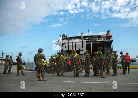 U.S. Marines with III Marine Expeditionary Force and U.S. Army soldiers with 1st Battalion, 1st Air Defense Artillery, gather outside the USNS Guam (T-HST-1) in preparation for a Joint Mobility Exercise at Naha Military Port, Okinawa, Japan, April 21, 2021. The exercise tested the capability of lift support to units and gear that are uncommon to traditional Marine Corps conveyance planning. Stock Photo