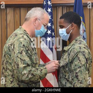 JACKSONVILLE, Fla. (April 22, 2021) - U.S. Navy Surgeon General Rear Adm. Bruce Gillingham frocks Hospitalman Christian Cisse to Hospital Corpsman 3rd Class Cisse during an Admiral’s Call for a group of sailors from Naval Hospital Jacksonville and Navy Medicine Readiness and Training Command Jacksonville onboard NAS Jacksonville on April 22. Stock Photo