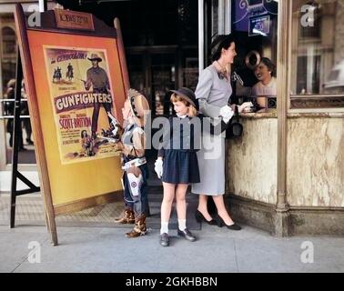 1950s MOTHER 2 CHILDREN BUYING TICKETS TO MOVIE MATINEE BOY WEARING COWBOY COSTUME - j5858c DEB001 HARS OUTDOOR COWBOY TOGETHER COSTUME 3 MOVIE PICTURE MOM CLOTHING SHOW CINEMA POSTER NOSTALGIC FILM PAIR GLOVE SUBURBAN URBAN THEATER RELATIONSHIP MOTHERS OLD TIME NOSTALGIA BROTHER MOVING SHOOTING OLD FASHION SISTER 1 JUVENILE STYLE COMMUNICATION CASHIER GUNS BILLBOARD WEST SONS TICKETS LIFESTYLE PARENTING FEMALES TICKET BROTHERS RELATION GROWNUP COPY SPACE PEOPLE CHILDREN FRIENDSHIP FULL-LENGTH LADIES SHOOT DAUGHTERS PERSONS INSPIRATION GROWN-UP CHARACTER MALES WESTERN ENTERTAINMENT SIBLINGS Stock Photo