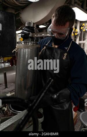 PACIFIC OCEAN (April 22, 2021) Machinist’s Mate 3rd Class Michael Smith, from Atlanta, pulls out a strainer in the aft engine room of amphibious assault ship USS Essex (LHD 2), April 22. Essex is underway conducting routine operations in U.S. Third Fleet. Stock Photo