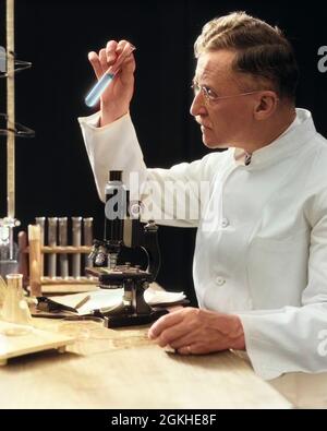 1920s 1930s 1940s MAN SCIENTIST LAB TECHNICIAN IN WHITE COAT LOOKING AT TEST-TUBE IN FRONT OF MICROSCOPE - l1244c HAR001 HARS NOSTALGIA MICROSCOPE OLD FASHION 1 ANGER SLIDE TECHNOLOGY DISH INFORMATION MYSTERY TUBE ANNOYED STUDIO SHOT LABORATORY FULL-LENGTH WISE PETRI PROFESSION AMERICANA EYEGLASSES MIDDLE-AGED DISCOVERY ARCHIVAL SCIENTIFIC WISDOM CITIZEN KNOWLEDGE PROGRESS EXAMINE SENIOR CITIZEN FRUSTRATION INVESTIGATE METHOD OCCUPATIONS BREAKTHROUGH INSPECTOR INVESTIGATOR MANLY SEEKING SPECIMEN STARE PETRI DISH SOLITARY DISCOVER FLASK INSPECT LAB COAT MAD SCIENTIST MID-ADULT MID-ADULT MAN Stock Photo