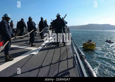 PLYMOUTH, England (April 23, 2021) Sailors aboard the Arleigh Burke-class guided-missile destroyer USS Ross (DDG 71) moor the ship to a buoy in Plymouth, England during Flag Officer Sea Training (FOST), April 23, 2021. FOST is a three-week exercise led by the Royal Navy that tests the ship’s warfighting ability. Ross, forward-deployed to Rota, Spain, is on patrol in the U.S. Sixth Fleet area of operations in support of regional allies and partners and U.S. national security interests in Europe and Africa. Stock Photo