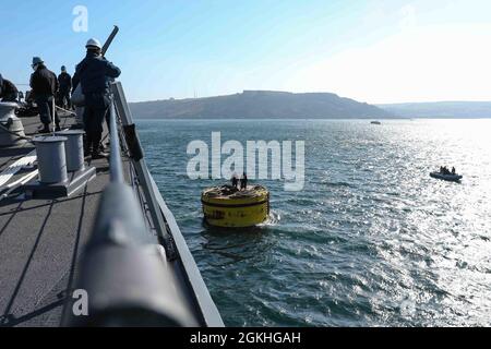 PLYMOUTH, England (April 23, 2021) Sailors aboard the Arleigh Burke-class guided-missile destroyer USS Ross (DDG 71) moor the ship to a buoy in Plymouth, England during Flag Officer Sea Training (FOST), April 23, 2021. FOST is a three-week exercise led by the Royal Navy that tests the ship’s warfighting ability. Ross, forward-deployed to Rota, Spain, is on patrol in the U.S. Sixth Fleet area of operations in support of regional allies and partners and U.S. national security interests in Europe and Africa. Stock Photo