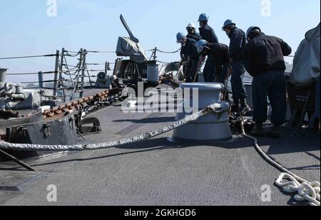 PLYMOUTH, England (April 23, 2021) Sailors aboard the Arleigh Burke-class guided-missile destroyer USS Ross (DDG 71) moor the ship to a buoy in Plymouth, England during Flag Officer Sea Training (FOST), April 23, 2021. FOST is a three-week exercise led by the Royal Navy that tests the ship’s warfighting ability. Ross, forward-deployed to Rota, Spain, is on patrol in the U.S. Sixth Fleet area of operations in support of regional allies and partners and U.S. national security interests in Europe and Africa. Stock Photo