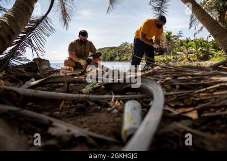 INALÅHAN, Guam (April 23, 2021) Lt. Cmdr. Andrew Regalado (right), from New York City, and Fire Control Technician 2nd Class Patrick Trevino, from Versailles, Kentucky, both assigned to Commander, Submarine Squadron 15, collect trash off the beach. CSS-15 and Naval Submarine Training Center Pacific, Detachment Guam, joined forces with their sister village, Inalåhan, during a volunteer event focused on environmental cleanliness to recognize Earth Day. Stock Photo