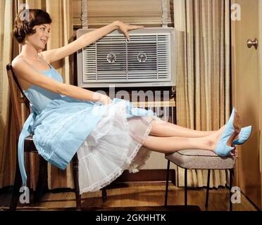 1960s SMILING WOMAN SITTING PROPPING LEGS UP ON STOOL RESTING HAND ON TOP OF LOOKING AT AIR CONDITIONER - s11466c DEB001 HARS LUXURY COPY SPACE FULL-LENGTH B&W SUMMERTIME COMFORT CONDITIONER DREAMS HAPPINESS COMFORTABLE UNIT CONDITIONING UP AIR CONDITIONING AIR CONDITIONER ESCAPE AC COOLING OFF DEB001 CLIMATE CONTROL PEOPLE WOMEN COOLING PROPPING REFRESHING RELAXATION RELIEF YOUNG ADULT WOMAN BLACK AND WHITE CAUCASIAN ETHNICITY CLIMATE HEAT WAVE OLD FASHIONED Stock Photo