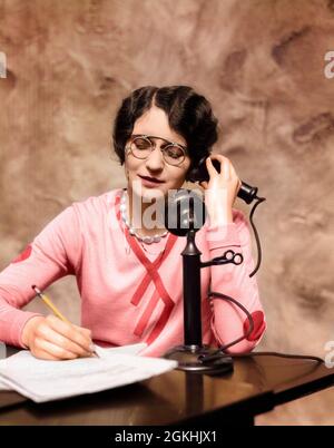 1920s WOMAN WEARING PINCE-NEZ GLASSES SITTING AT DESK TALKING ON CANDLESTICK PHONE AND WRITING - t2265c HAR001 HARS LISTEN FEMALES VERTICAL GROWNUP HOME LIFE COMMUNICATING SPEAK WRITE CHAT CANDLESTICK WOMAN'S RELEASES OFFICES OPTICAL TELEPHONING CHATTER CUSTOMER SERVICE WOMAN'S LIBERATION WOMEN'S RIGHTS LIB PENCILS WOMAN'S RIGHTS WOMEN'S LIB WOMEN'S LIBERATION CANDLESTICK PHONE RIGHTS PINCE-NEZ OCCUPATIONS OFFICE MACHINE PHONES CONNECTION TELEPHONES PHONING SECRETARIES STYLISH WRITER LIBERATION WOMEN'S ADMINISTER COMMUNICATE MID-ADULT MID-ADULT WOMAN YOUNG ADULT WOMAN CAUCASIAN ETHNICITY Stock Photo