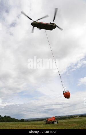 A California Army National Guard CH-47 Chinook aircraft takes off for a helicopter bucket training exercise from Allen Helibase near Sutter Creek, California, April 24, 2021.  Cal Guard aircraft and flight crews prepare to be activated during California’s fire season and use this training with CAL FIRE military helicopter manager students and instructors to learn to safely and effectively execute water drops to fight wildfires. Stock Photo