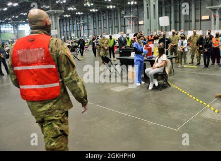 The 500,000th Covid-19 vaccination syringe is brought to the vaccination station by New York Army National Guard Pfc Christopher Moreno  a member of  the 1569th Transportation Company prior to being administered on April 26, 2021. This syringe marks the 500,000-vaccine administered at the Jacob Javits Center mass vaccination site to Cassie Huang, 28, of Manhattan, NY. The New York State Department of Health vaccination efforts for New York residents began January 13, 2021 at the Javits Vaccination Site. Over 3,180 members of the New York Army and Air National Guard, the New York Naval Militia Stock Photo