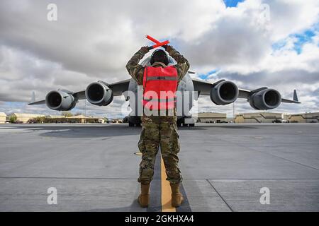 Senior Airman Antoine Barnes, 821st Contingency Response Squadron fire team member, marshals a C-17 Globemaster III from Joint Base Lewis-McChord, Washington, April 27, 2021, on the flight line at Mountain Home AFB, Idaho. Barnes participated in exercise Rainier War, testing his abilities to employ air combat capabilities during a time of potentially imminent foreign aggression. Stock Photo