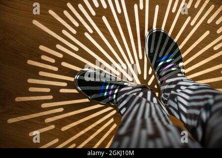 Star-shaped shadows on legs with gray pants and black sneakers with colored laces Stock Photo