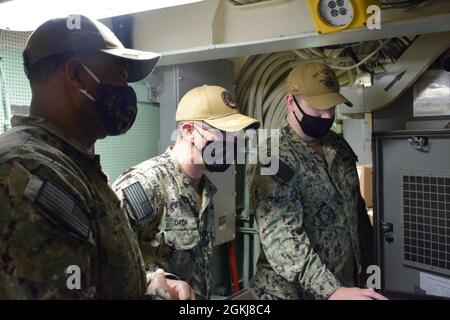 210430-N-PS0730-1017: ET2 Austin Miller, lead technician of the Global Positioning Navigation and Timing Service (GPNTS), demonstrates the user interface of the Global Positioning Navigation and Timing Service (GPNTS) system to Rear Adm. John Okon and Cmdr. Ray Glenn. Okon visited the USS Gonzalez (DDG 66) to discuss with technicians about the operation and maintenance of the GPNTS system from a technicians point of view in order to provide insight for the future development of the system. Stock Photo