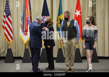 John Hall, Headquarters Department of the Army G4 principal deputy (left), presents Sydney Smith, Army Logistics University president, with the senior executive service pin Friday, April 30, 2021, at the Army Logistics University Green Auditorium. Smith's husband, Tim, and daughter, Molly, watch the presentation. Members of the SES serve in the key positions just below the top presidential appointees and alongside general officers. Stock Photo