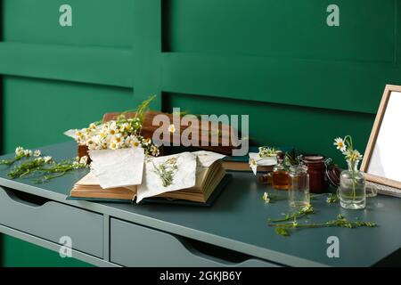 Book with dried chamomiles on table Stock Photo