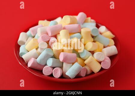 Plate with marshmallows on red background Stock Photo