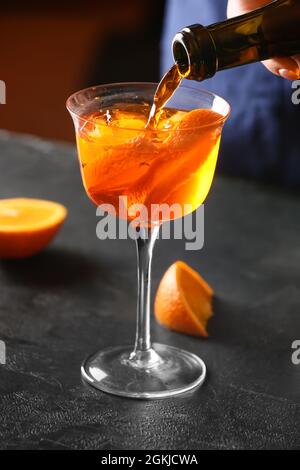 Woman preparing tasty aperol spritz cocktail at table, closeup Stock Photo