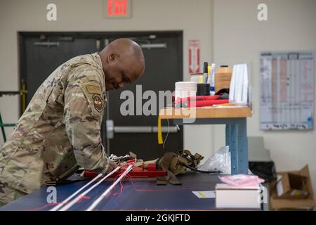 Tech. Sgt. Tyree Leverette, 403rd Operational Support Squadron aircrew flight equipment technician at Keesler Air Force Base, Miss., fastens the cords of a  BA-30 Low Profile Parachute system to an apparatus that facilitates the assembly and packing of the parachute into its backpack May 2, 2021. Gradually, the Air Force is making a branch-wide transition to the BA-30s for certain aircraft. Stock Photo